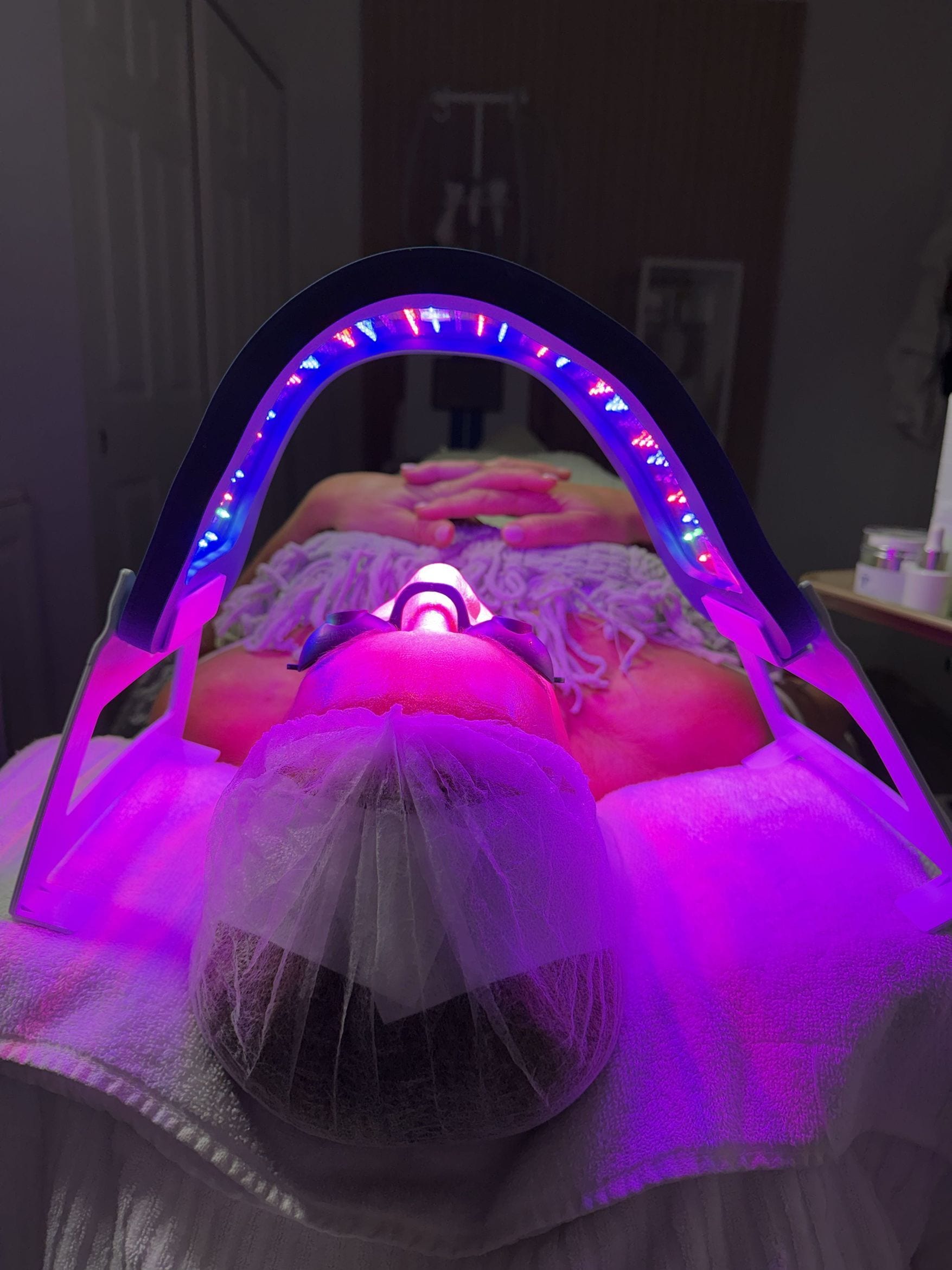 LED light therapy glowing over a client during a facial at the studio